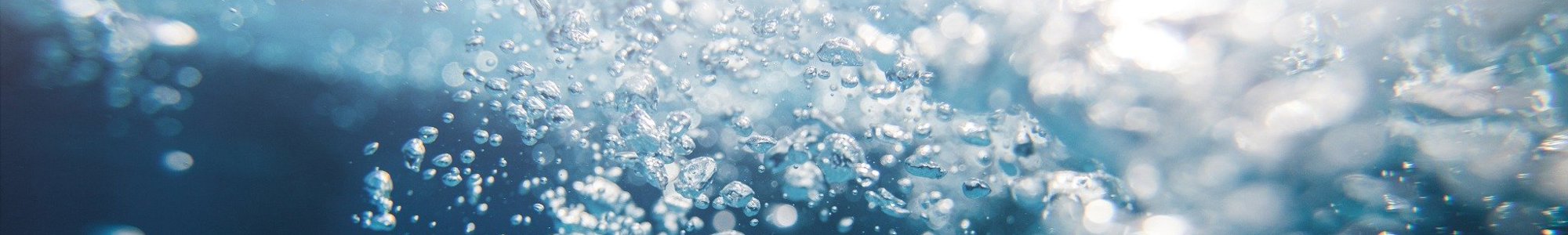 Underwater view with numerous rising air bubbles, illuminated by light from above, creating a dynamic and refreshing scene.